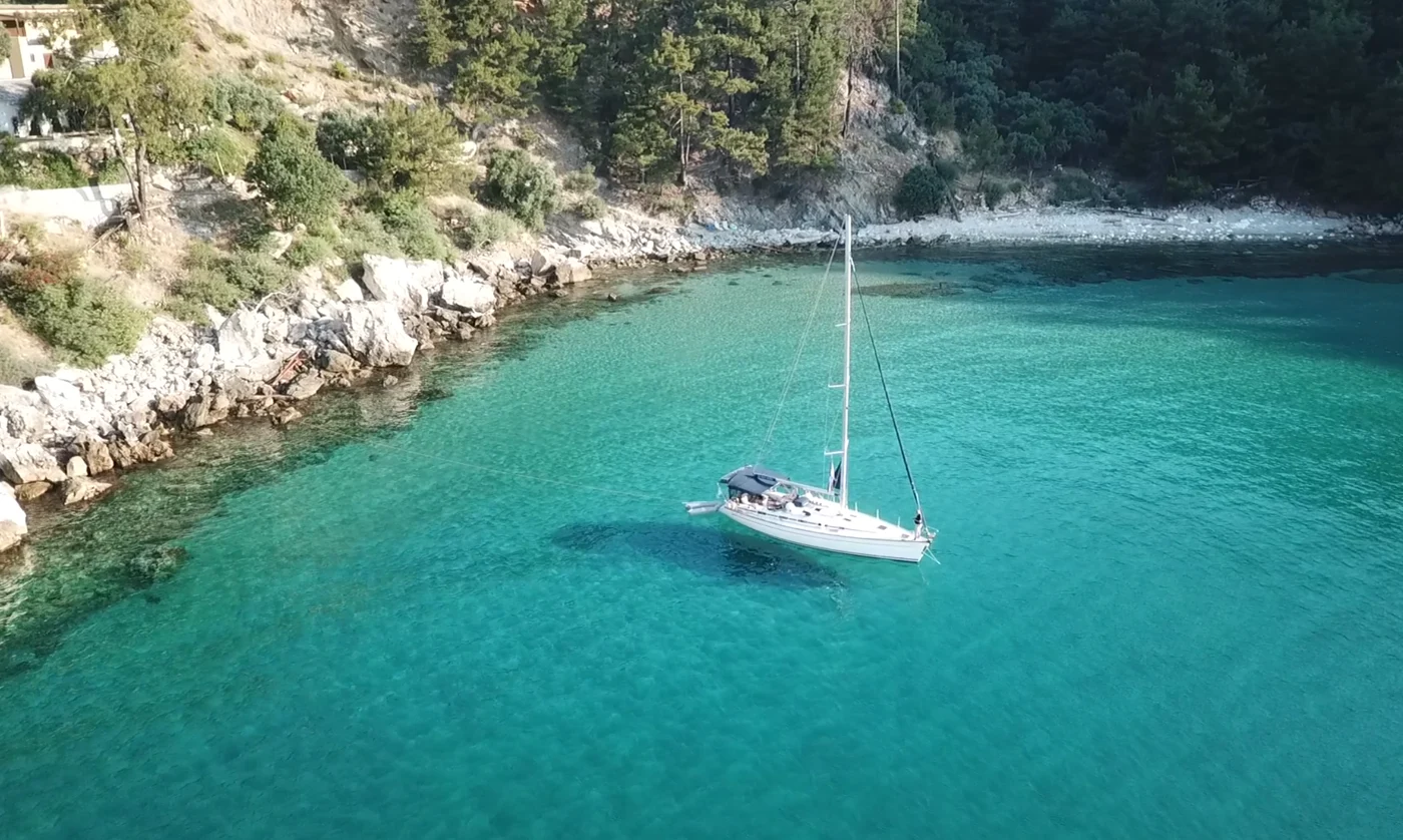 A sailboat at anchor in a clear turquoise bay