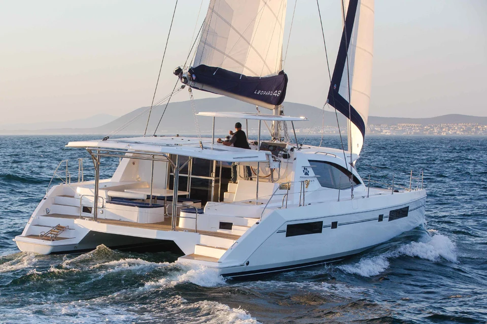 A sailing catamaran underway in evening light